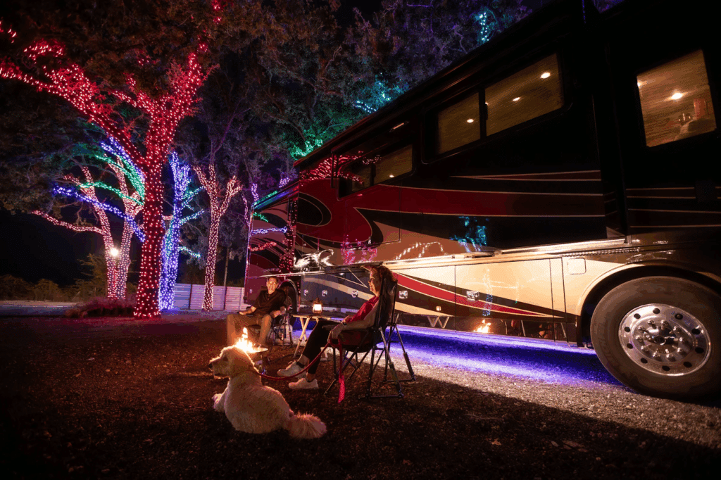 Couple sitting by a fire at their full hookup RV site in Madisonville, TX at Yuletide RV Park